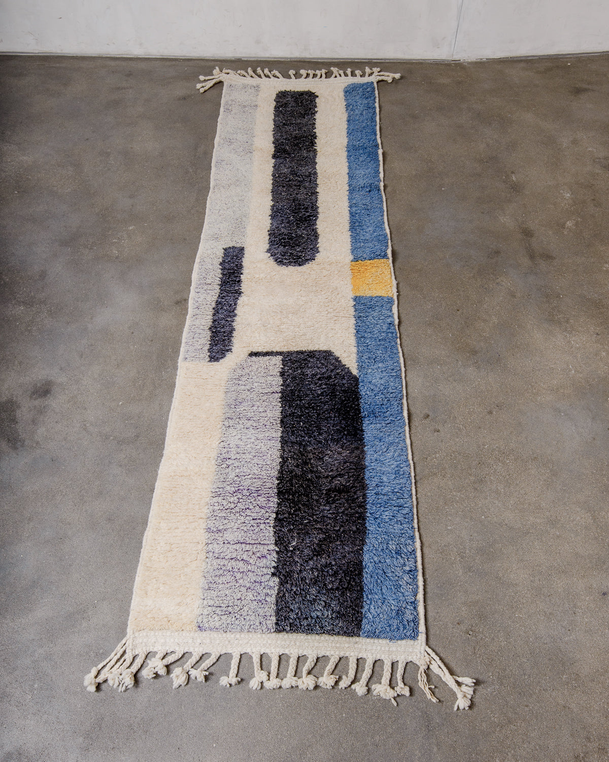 Berberlin runner rug made of sheep's wool, laying flat on concrete floor.